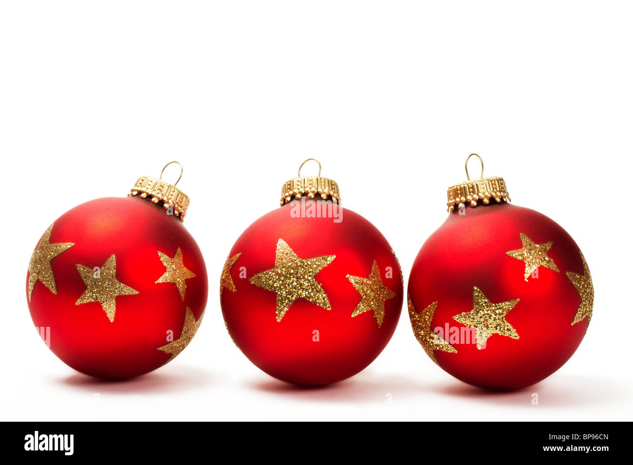 drei rote stumpf Weihnachtskugeln mit goldenen Glitzer Sternen auf weißem Hintergrund Stockfoto