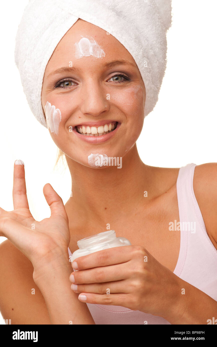 Frau Anwendung Gesichtscreme mit einem weißen Tuch umwickelt den Kopf Stockfoto