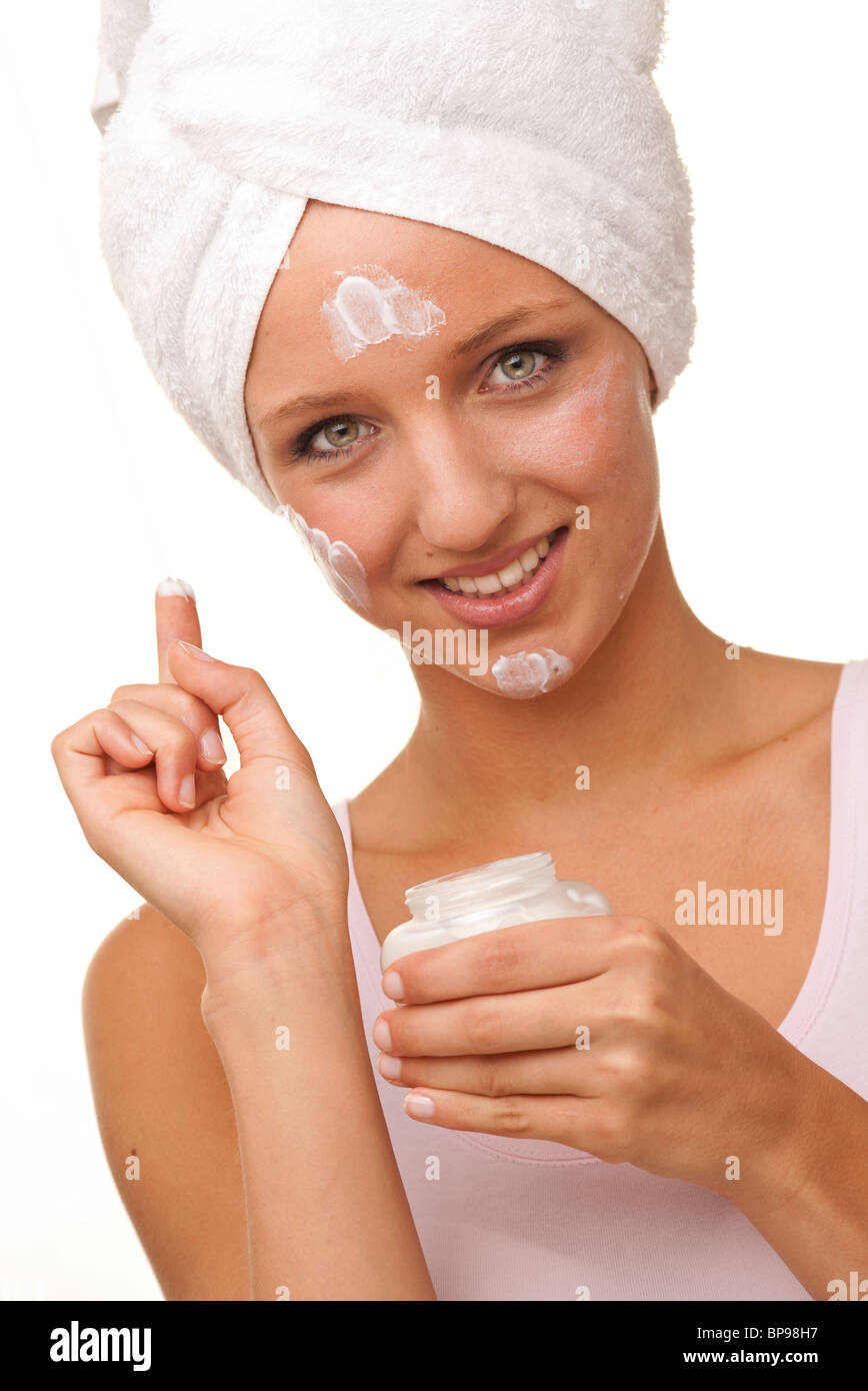 Frau Anwendung Gesichtscreme mit einem weißen Tuch umwickelt den Kopf Stockfoto