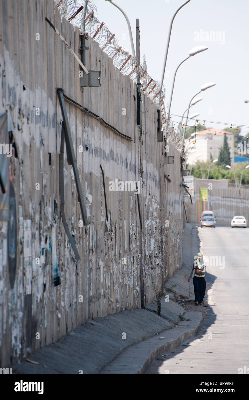 Ein einsamer Fußgänger Spaziergänge entlang der israelischen Trennmauer, die Ost-Jerusalem palästinensischen Stadtteil Al-Ram isoliert. Stockfoto