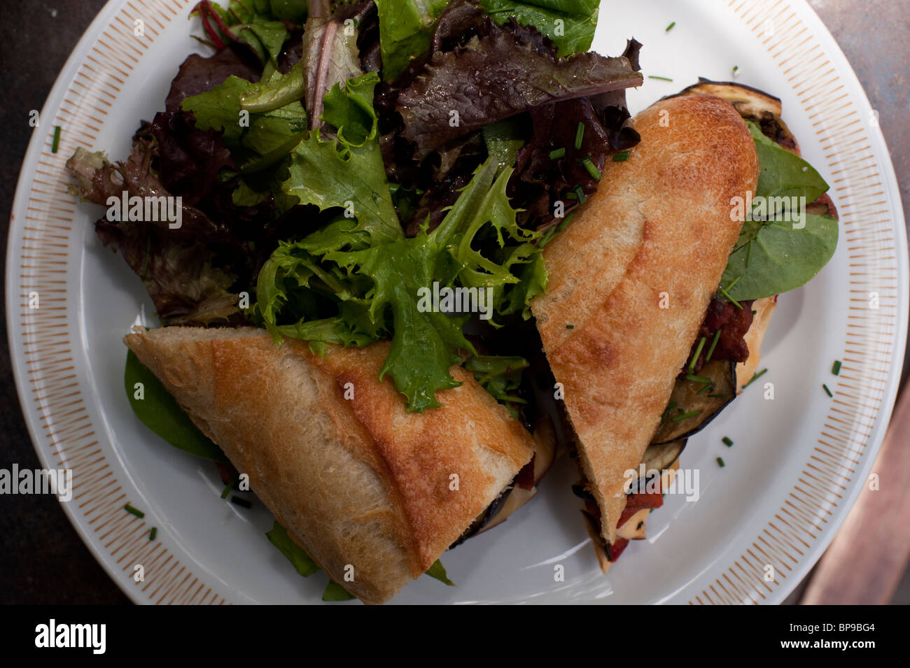 Gemischten Blattsalat und ein gegrilltes Gemüse und Käse-Sandwich auf Baguette Sauerteig machen ein gesundes Mittagessen in einem trendigen Café. Stockfoto