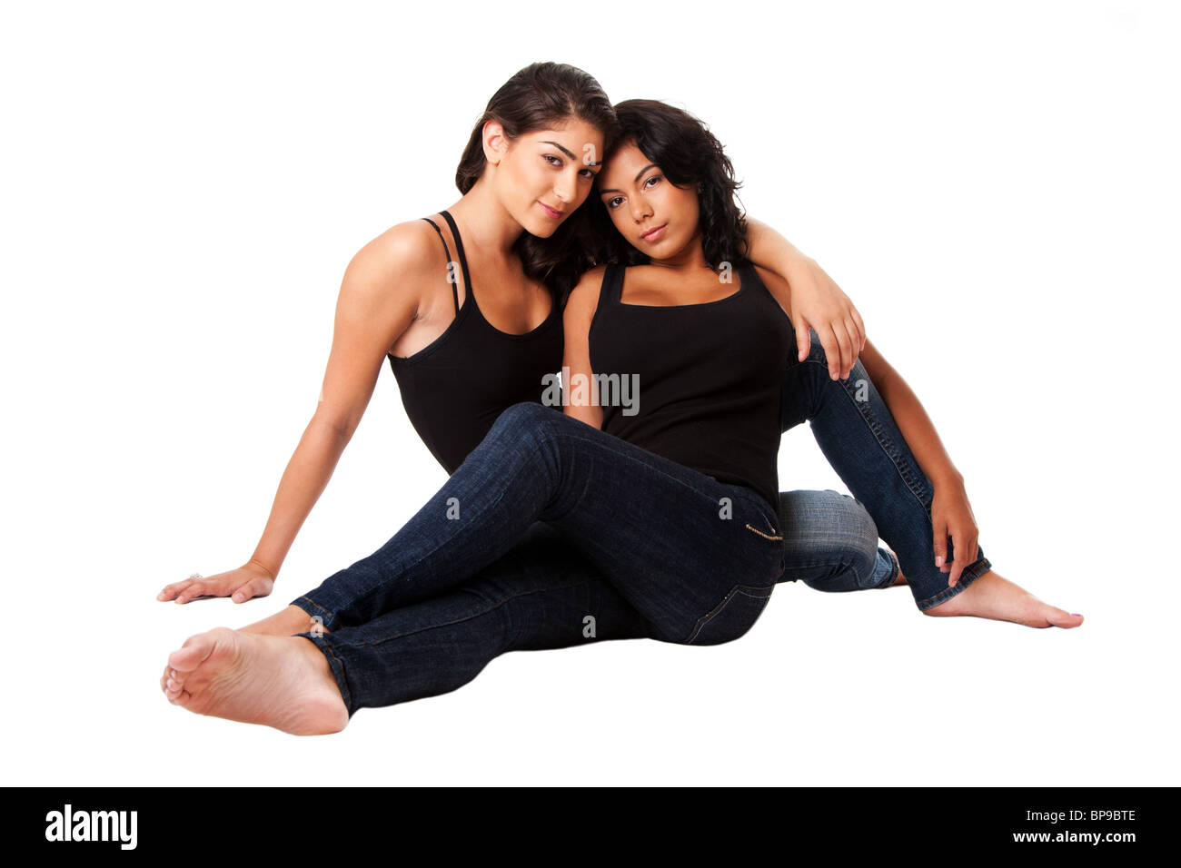 Schöne weibliche Mode paar sitzen zusammen tragen, blauen Jeans und schwarzen Tank-Top, isoliert. Stockfoto