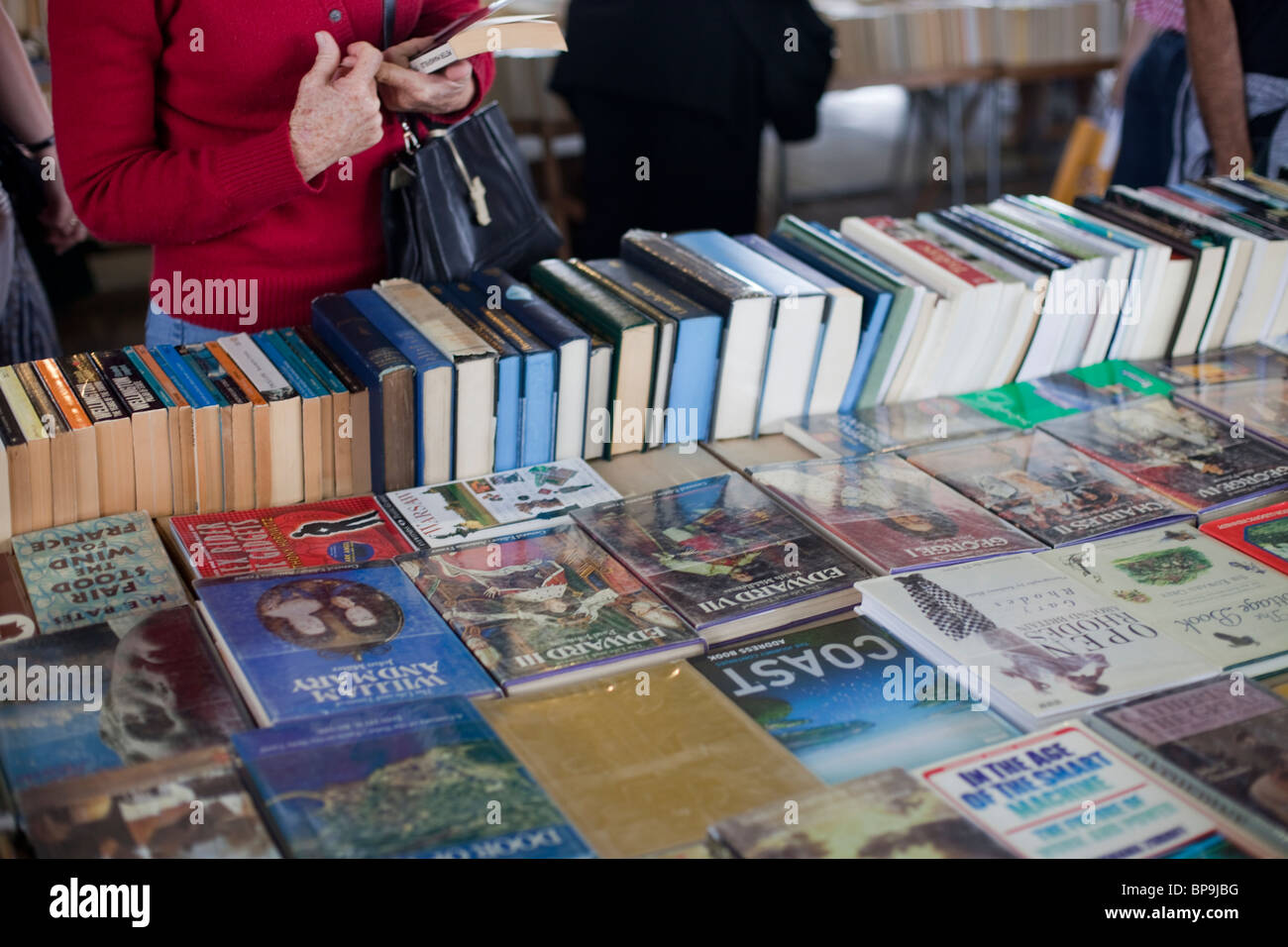 Eine Dame durchsucht einen Stall zu verkaufen gebrauchte Bücher am Südufer der Themse, London. Stockfoto