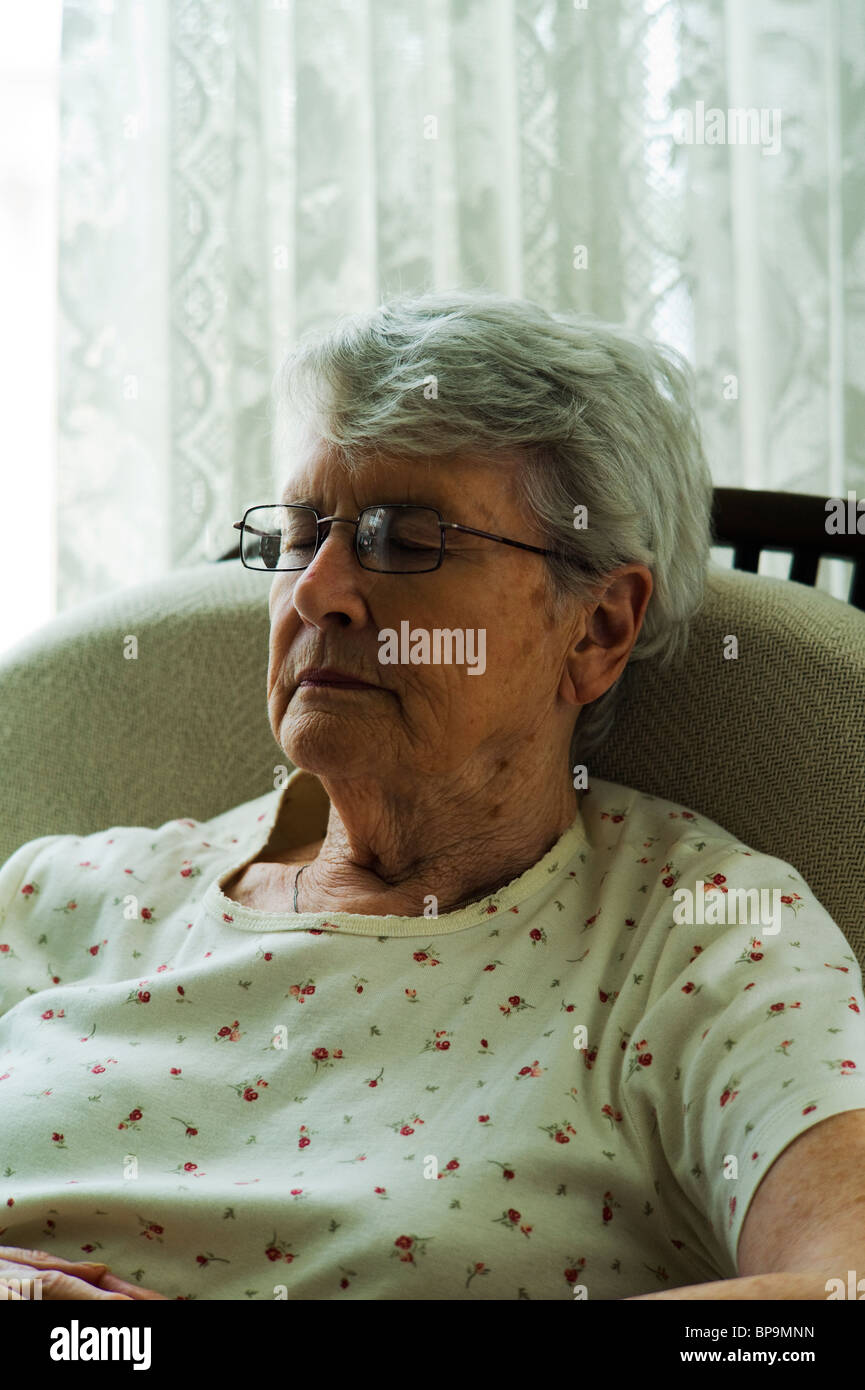 Alte Frau schlafen im Wohnzimmer Stuhl. Stockfoto