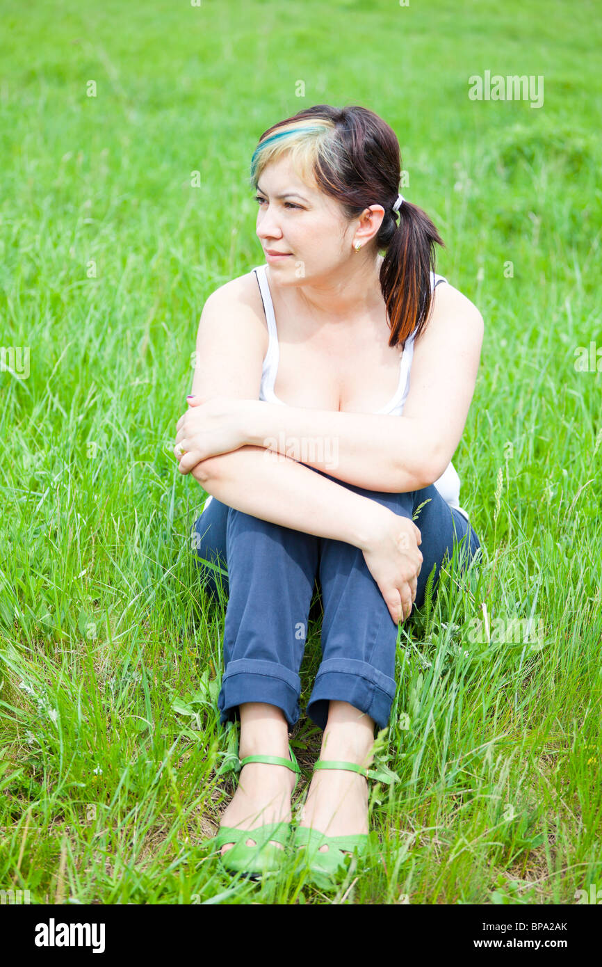 Junge Frau sitzen auf einer Wiese im park Stockfotografie