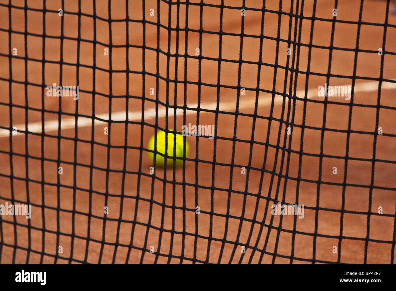 Sandplatz. Nahaufnahme der Tennisball durch das Netz zu sehen. Selektiven Fokus "Sdof". Horizontale Stockfoto