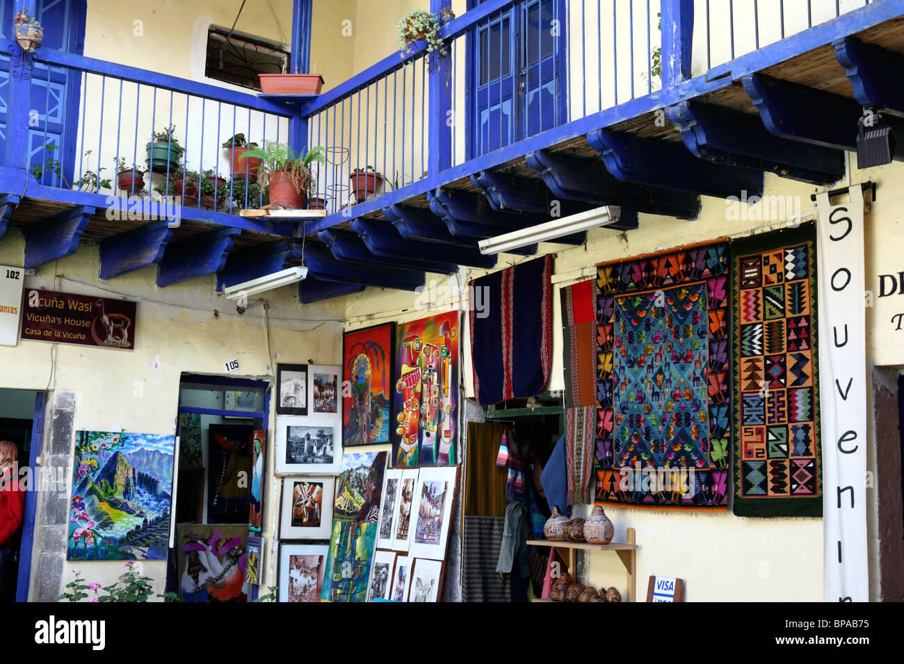 Gemälde und Webungen zum Verkauf in einem Handwerksladen im traditionellen kolonialen Innenhof, Cusco, Peru Stockfoto