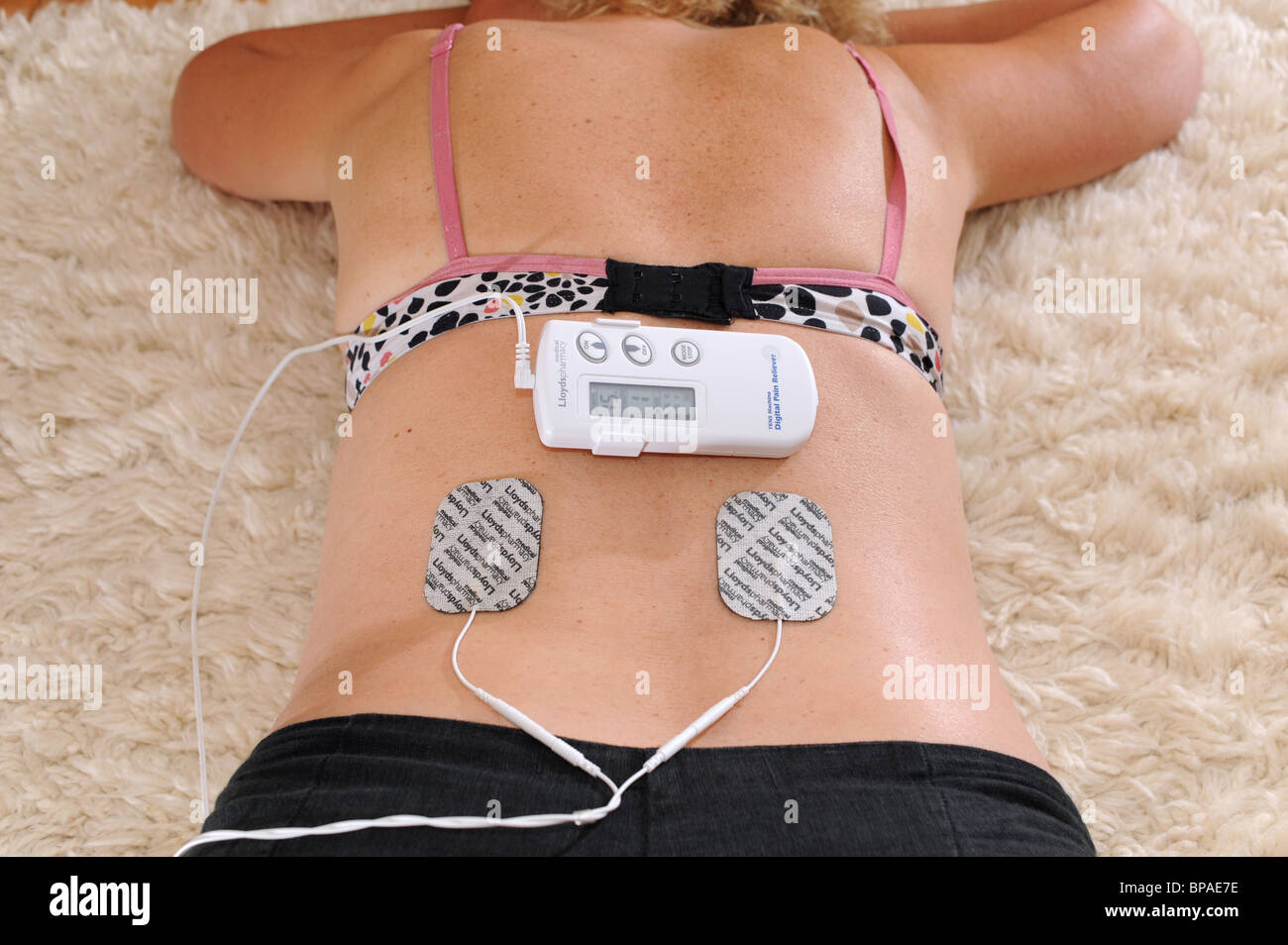 Frau Frau mit Lloyds Pharmacy TENS digitale Schmerzmittel mit Muskel helfen im Zusammenhang mit Verletzungen und Schmerzen im Rückenbereich 2010 Stockfoto