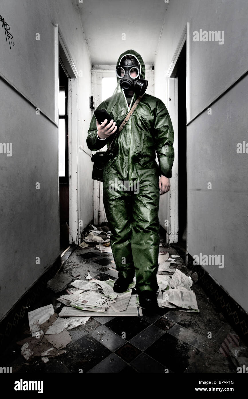 Ein Soldat trägt volle Schutzausrüstung und Gasmaske Wanderungen durch eine verlassene Residenz Messung der radioaktiven Strahlung. Stockfoto