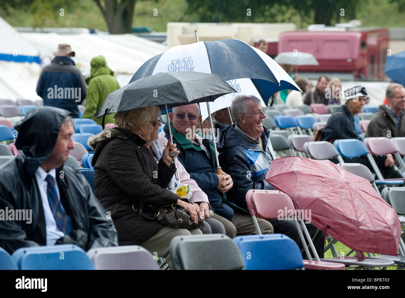 Shrewsbury Flower Show 2010 Besucher amüsieren sich unter Sonnenschirmen im strömenden Regen, Shropshire, UK Stockfoto