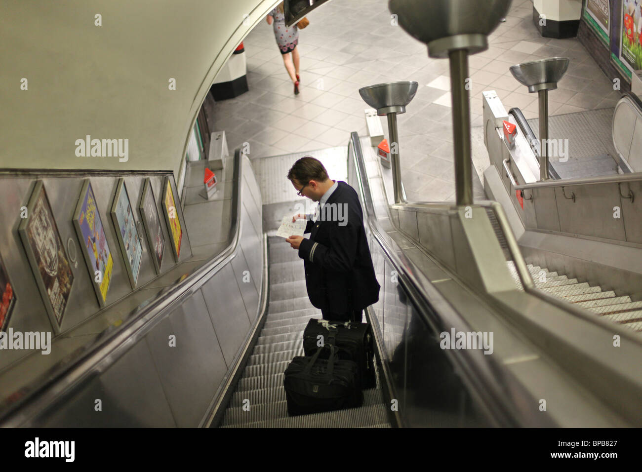Ein Pendler liest ein Buch als er hinunter die Rolltreppe am u-Bahnhof Balham, London. Stockfoto