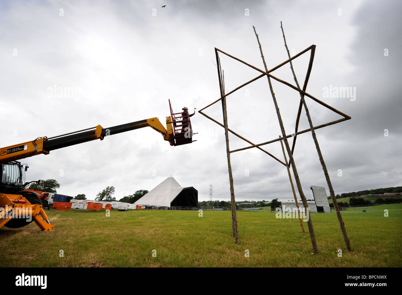 Ein Gerüstbauer errichtet einen Holz-Stern in der Nähe der Pyramide-Bühne auf dem Glastonbury Festival-Gelände Pilton UK Stockfoto