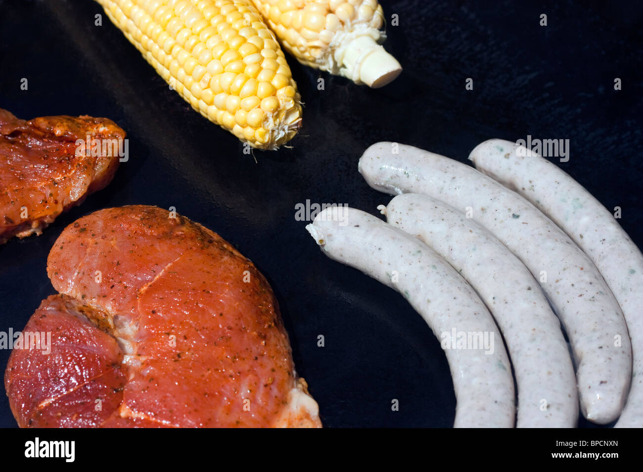 Rohes Fleisch, Wurst und Mais auf Gas-grill Stockfoto