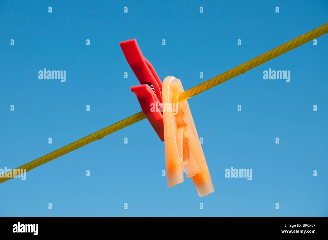 Roten und gelben Wäscheklammern auf eine Linie, blauen Himmel im Hintergrund Stockfoto