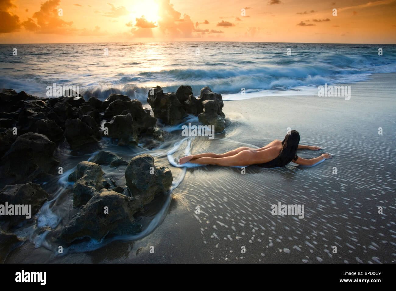 Junge nackte Frau am Strand in der Brandung liegen Stockfotografie - Alamy