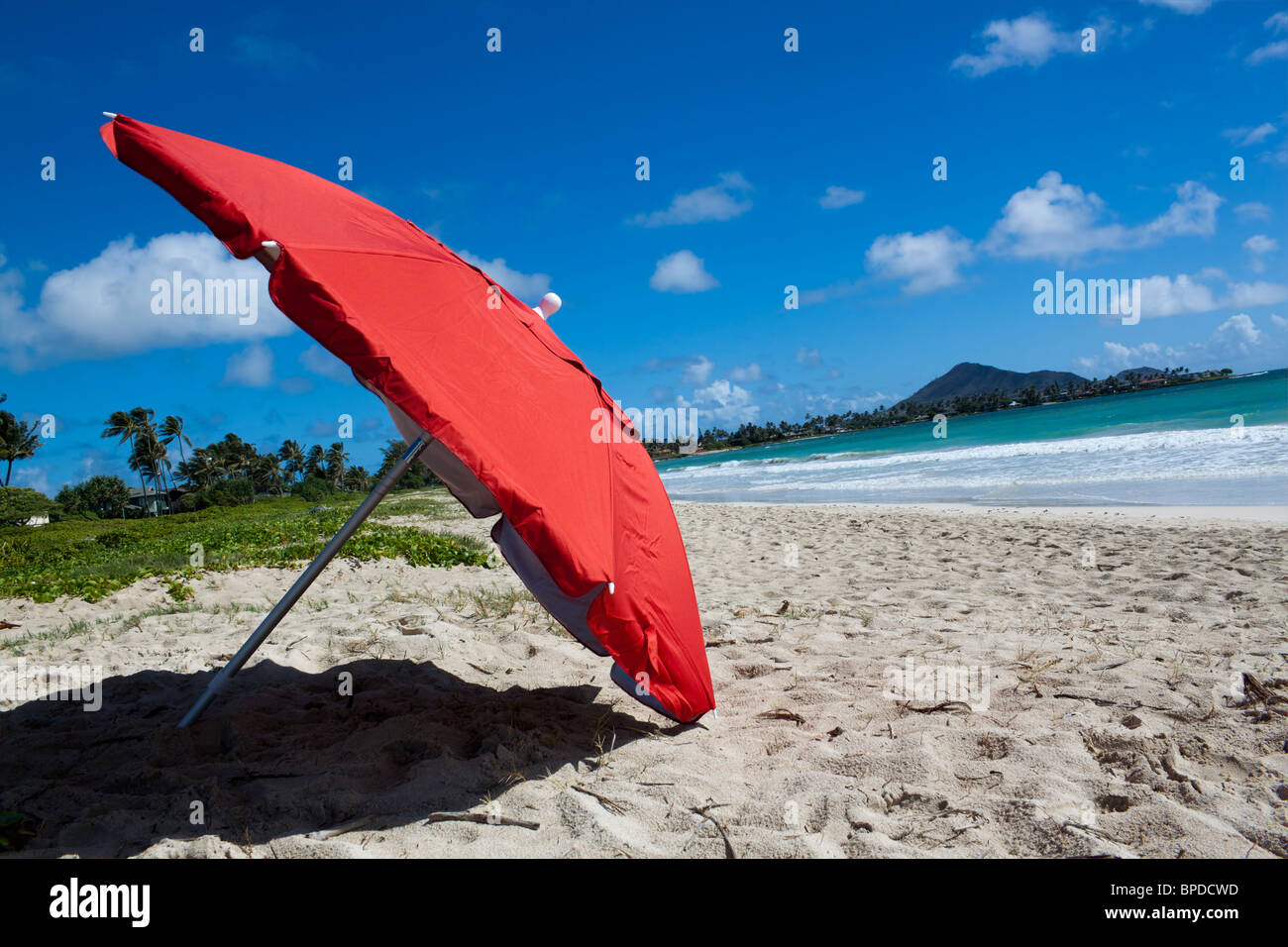 Roter Sonnenschirm am Strand mit Meer und Himmel im Hintergrund Stockfoto