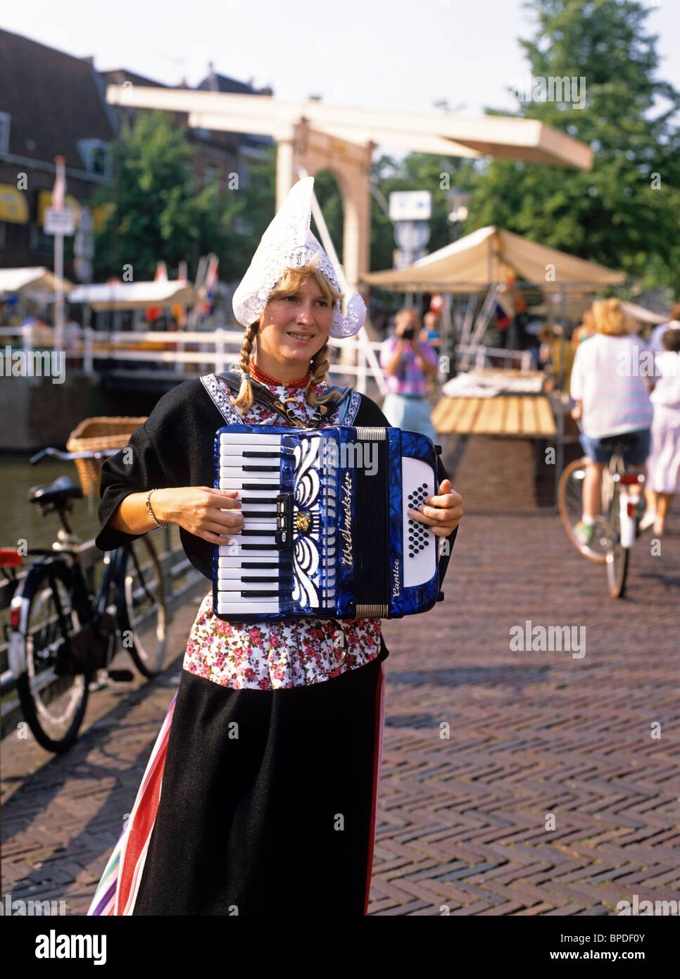 Straße Muscian in traditioneller Tracht, die neben einem Kanal in der Stadt Alkmaar durchführen Stockfoto