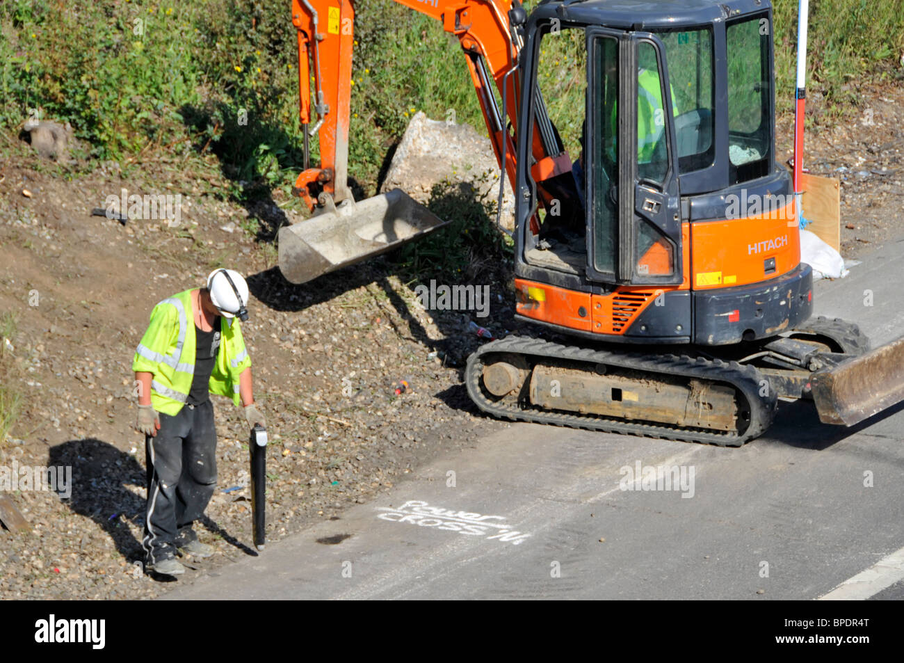Straßenbau M25 Autobahnarbeiter mit harten Schultern, der Handgeräte zur Ortung von Scopes und Kabeln verwendet, bevor der Bagger mit der Arbeit beginnt Brentwood Essex England Großbritannien Stockfoto