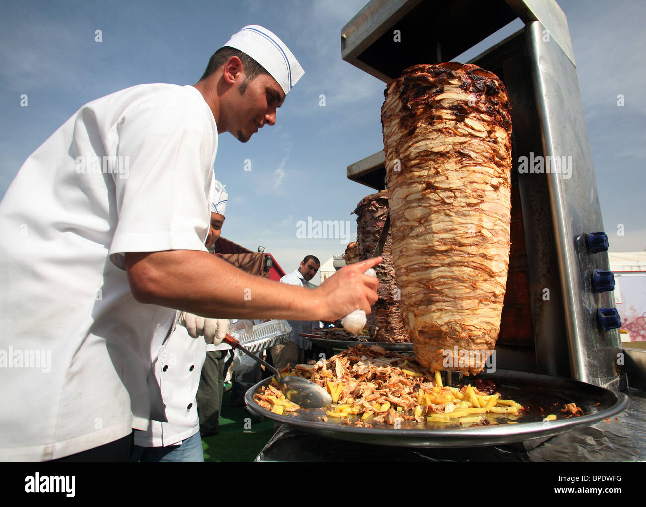 Ein Koch Schneiden von Fleisch aus einem Rotary spucken, Dubai, Vereinigte Arabische Emirate Stockfoto