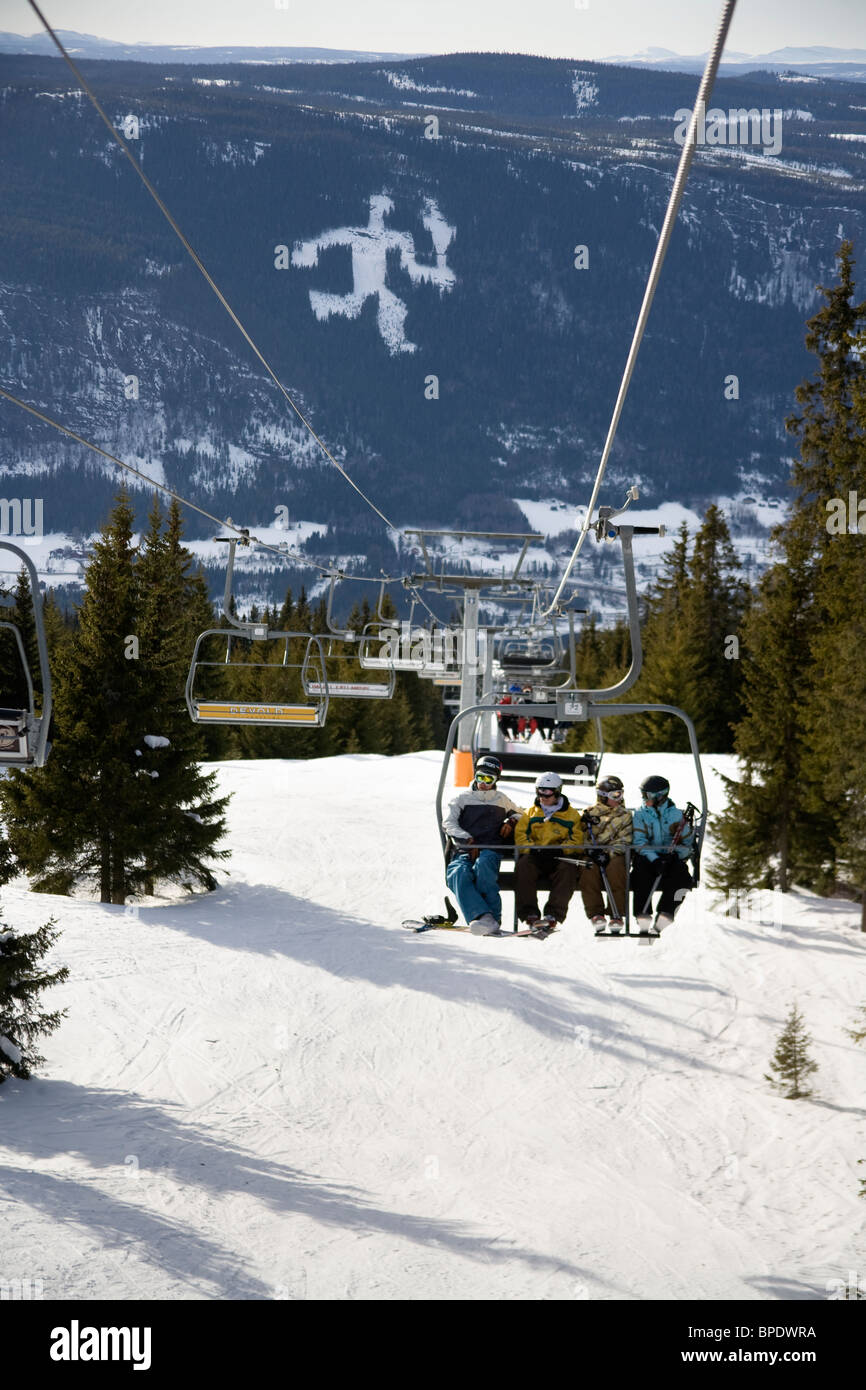 Skifahrer auf einer Hebebühne in Hafjell, Norwegen mit dem Lillehammer Olympische Symbol im Hintergrund. Stockfoto