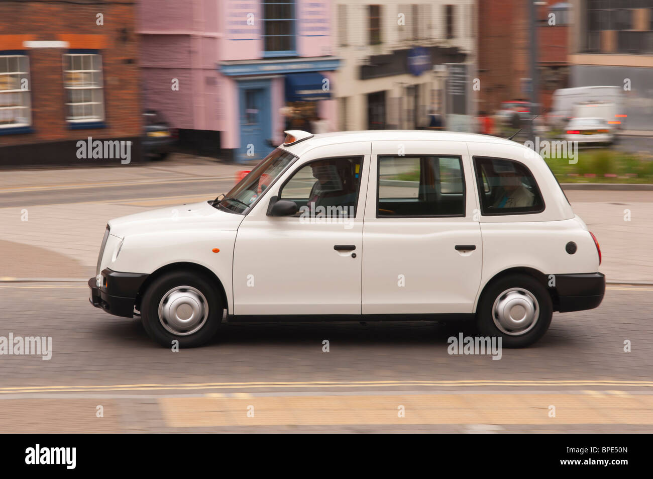 Eine weiße London Taxi cab Fahrt durch die Stadt und zeigt Bewegung in Norwich, Norfolk, England, Großbritannien, Uk Stockfoto