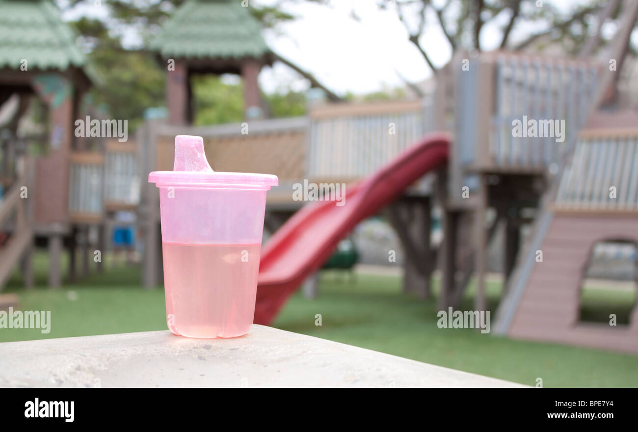 Rosa sippy Tasse mit Spielplatz im Hintergrund Stockfoto
