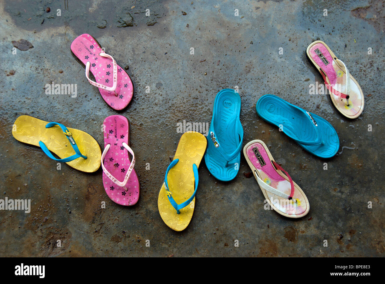 vier Paare von bunte Flip-Flops auf einem nassen Betonoberfläche in thailand Stockfoto