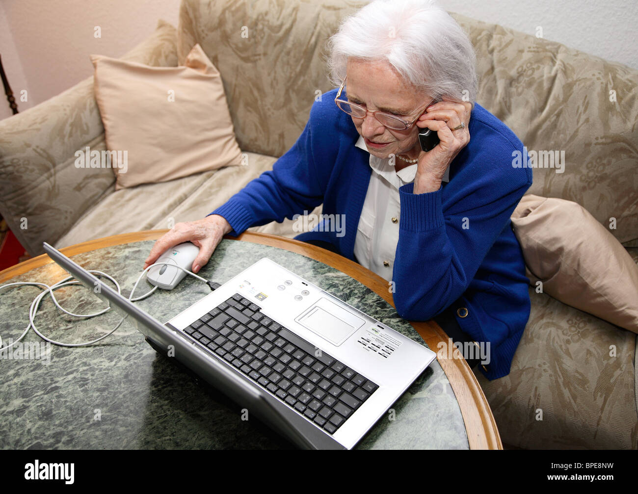 Ältere Frau mit einem Laptop und sprechen auf einem Handy Stockfoto