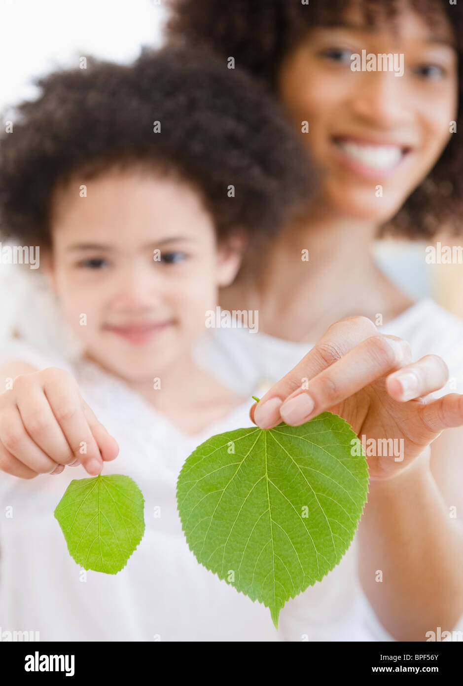 Mutter und Tochter hält grüne Blätter Stockfoto