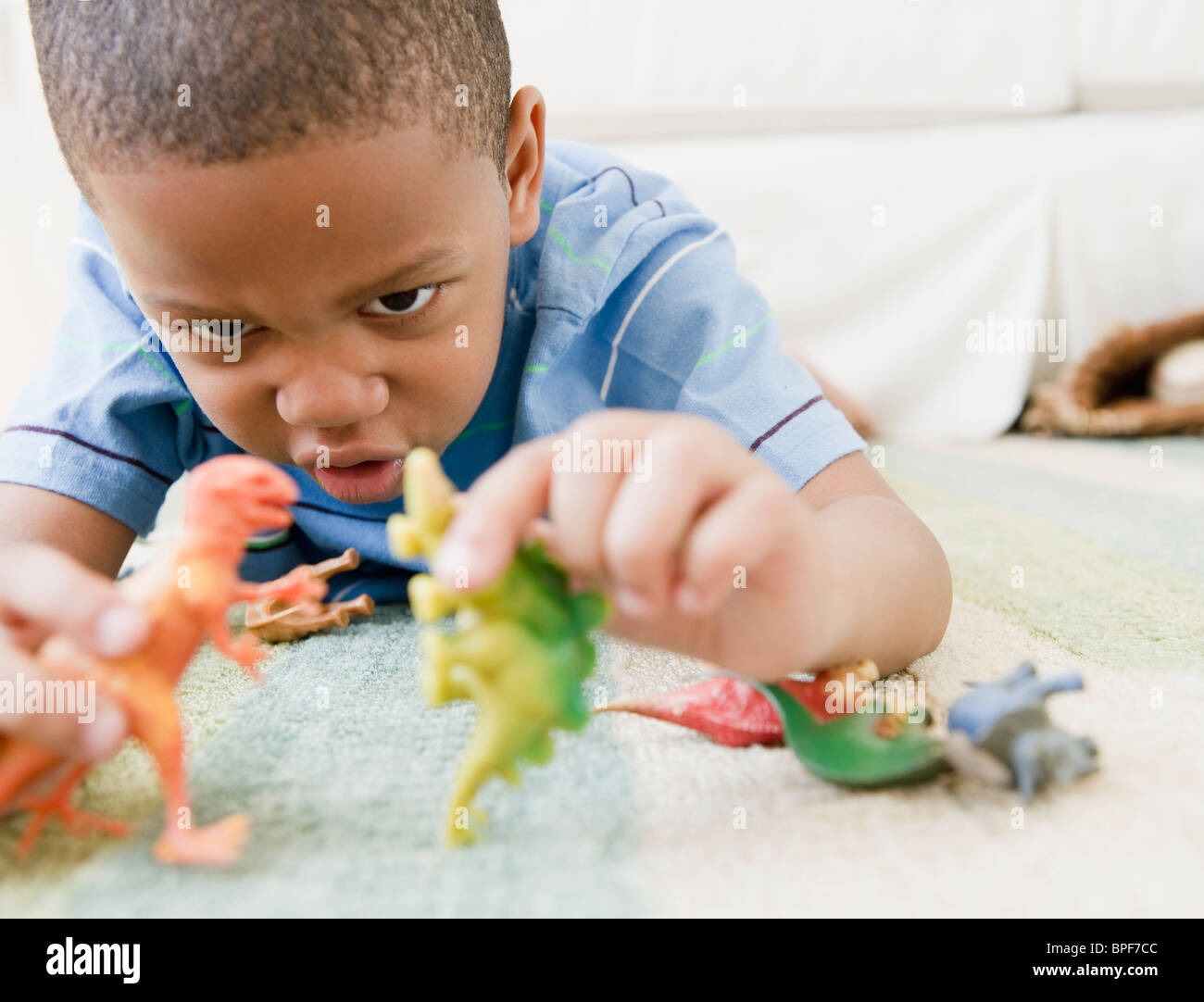 African American Boy auf Boden spielen mit Spielzeug Dinosaurier Stockfoto