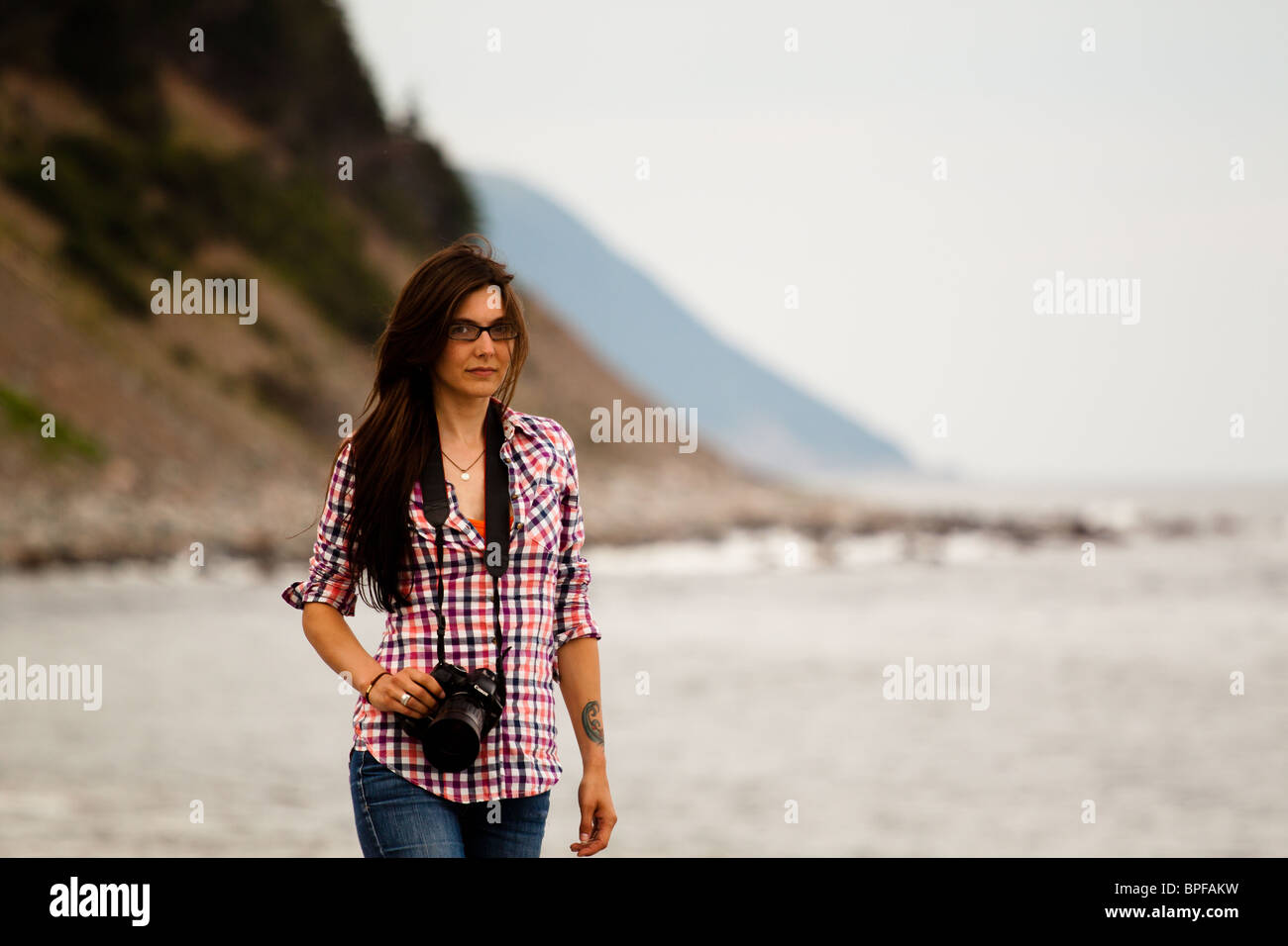 Ein junge Frau Fotografen posiert auf der Küste. Stockfoto