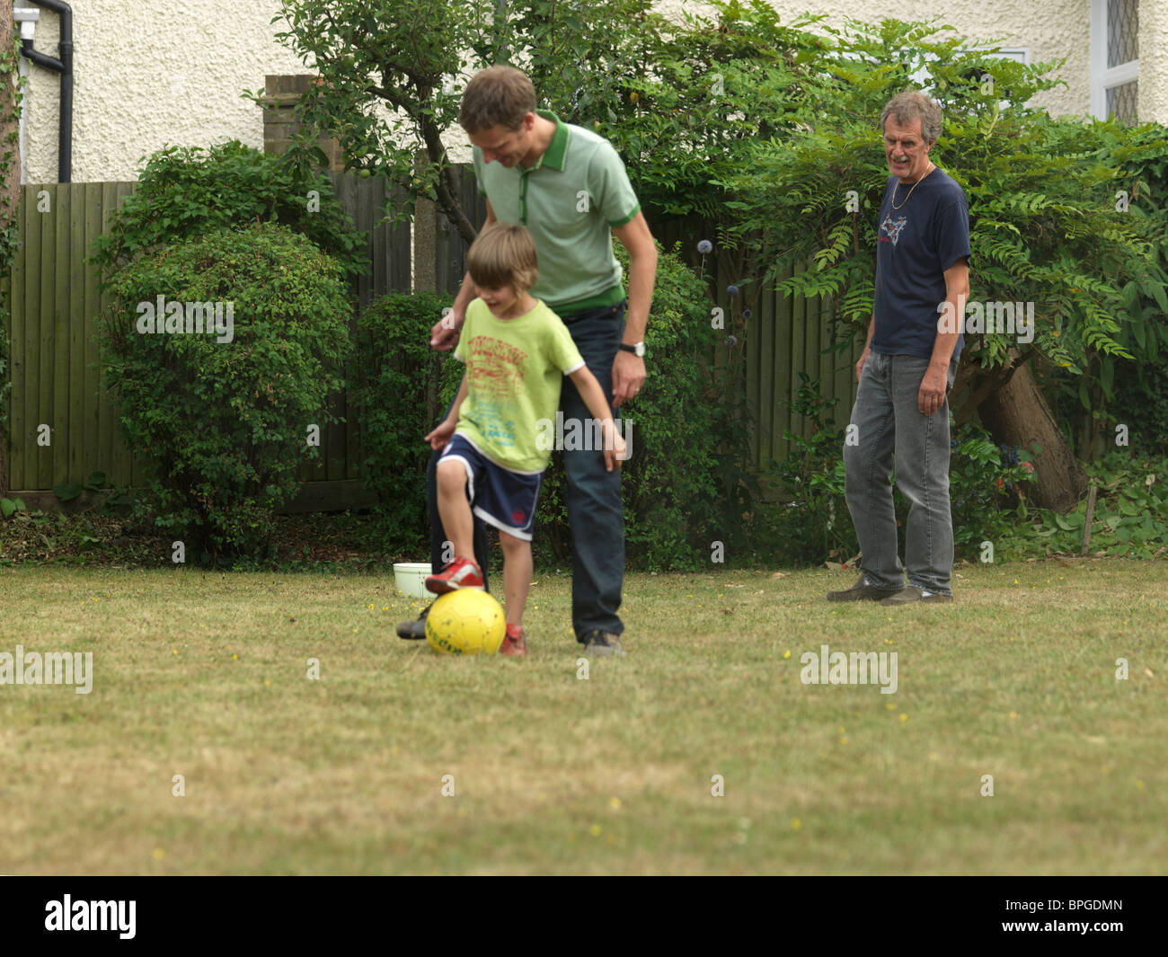 Kleiner Junge mit seinem Vater und Großvater im Garten Englands Fußball