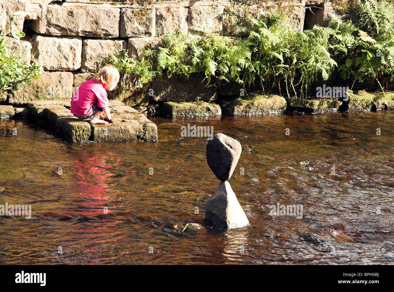 Kind durch den Fluss Hebden, Hebden Bridge, West Yorkshire, England, UK Stockfoto