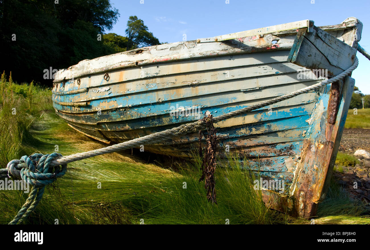 Ruderboot, links hoch und trocken in einer grasbewachsenen Bank bei Ebbe Stockfoto