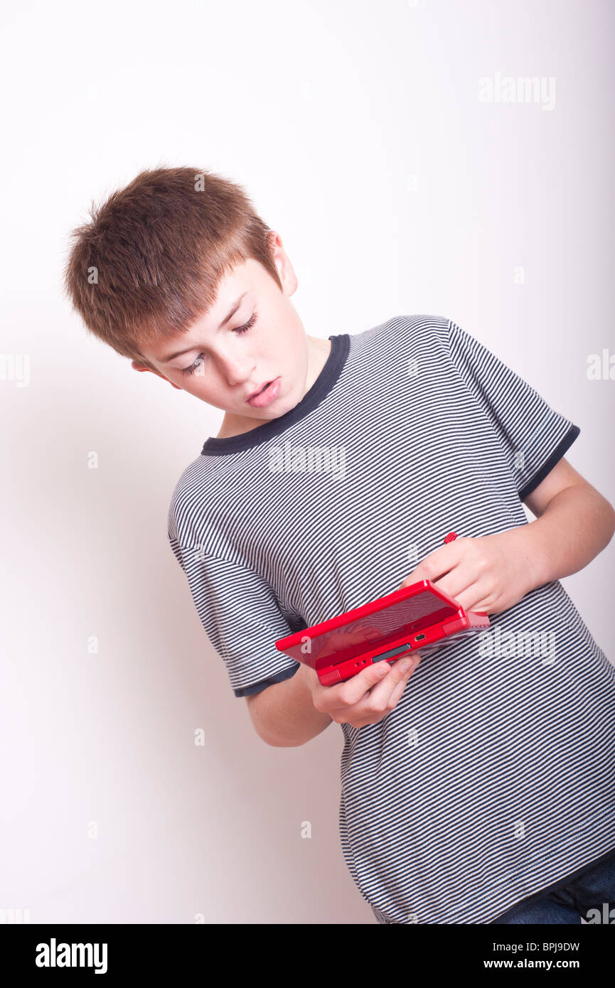 Ein MODEL Release Bild eines 10 Jahre alten Jungen mit einer Nintendo DS Handheld-Spielekonsole im Studio spielen Stockfoto