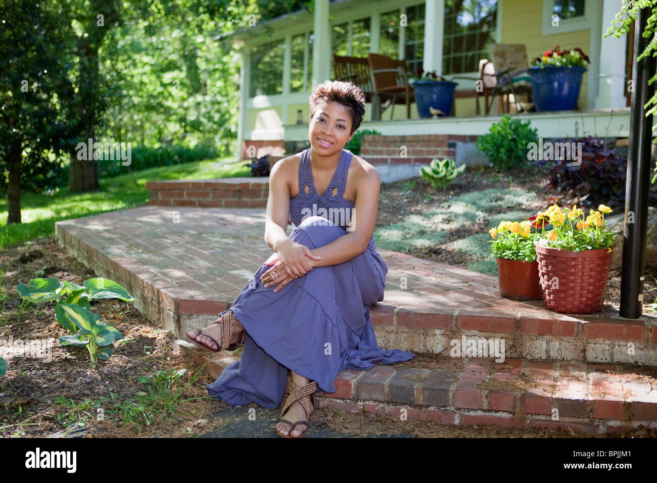 Schwarze Frau sitzt auf Schritt im Hinterhof Stockfoto