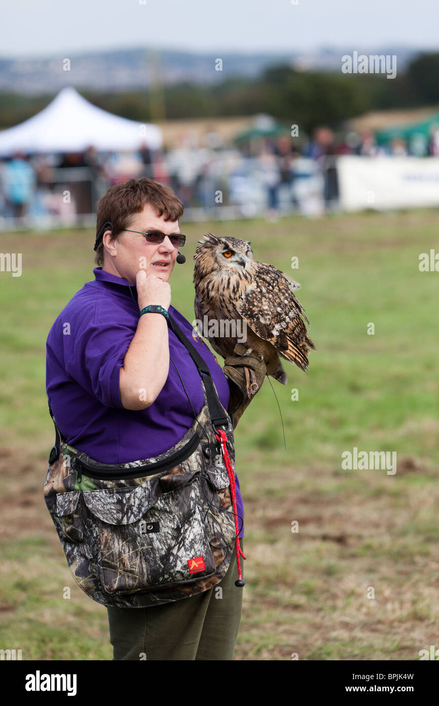 ein Vogel-Handler mit einer großen Eule auf einer öffentlichen Ausstellung. Stockfoto