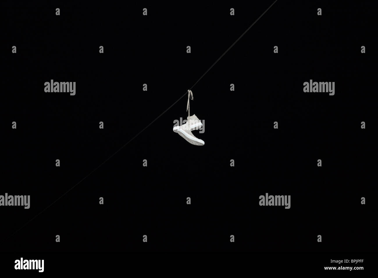 Weiße Turnschuhe Schuhe hängen von ihrer Schnürsenkel auf einem Draht in der Nacht Stockfoto