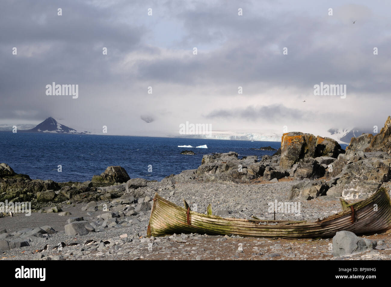 Ein altes Boot Walfang teilt der steinige Strand von Half Moon Island, Antarktis, mit Kinnriemen Pinguine. Stockfoto