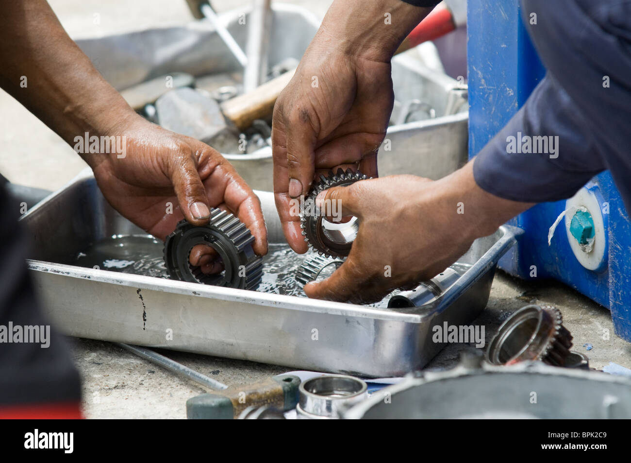 Händen von zwei Kfz-Mechaniker Getriebeteile in Benzin zu reinigen. Stockfoto