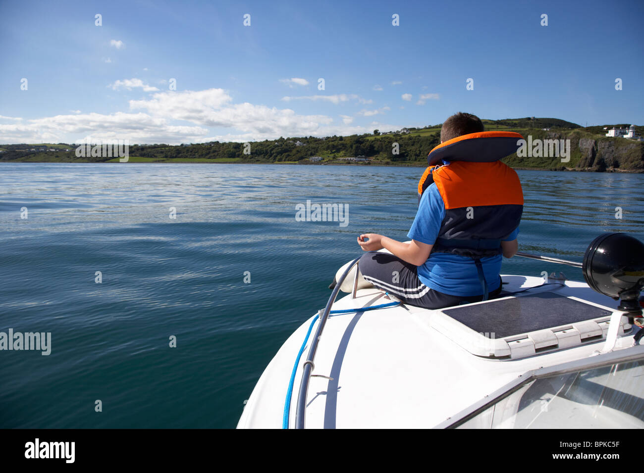 10 Jahre alter Junge tragen Rettungsweste ruhig sitzen auf der Vorderseite eines Schiffes auf hoher See Stockfoto