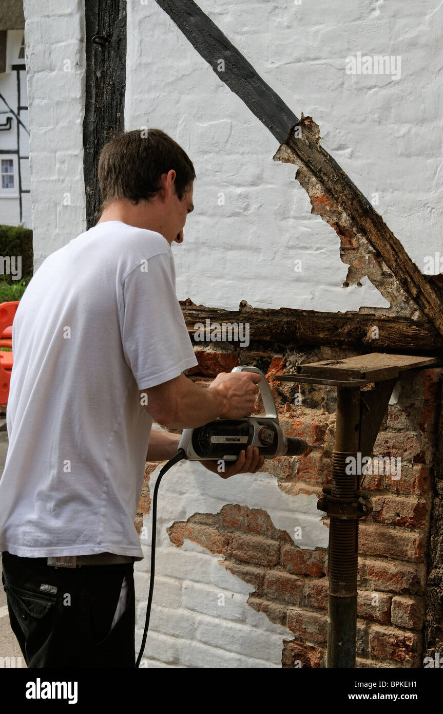 Renovierung einer alten Holz gerahmt denkmalgeschütztes Gebäude Arbeiter Ziegel entfernen & Rendern vor der Installation des neuen Eichenbalken Stockfoto