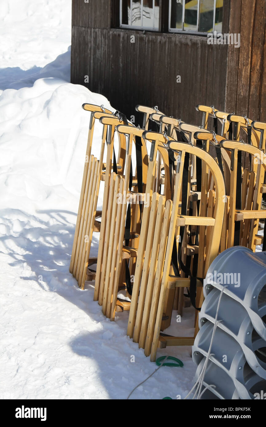 Der Rodel und Schlitten aufgereiht bereit zur Vermietung in einem Skigebiet in der Schweiz. Stockfoto