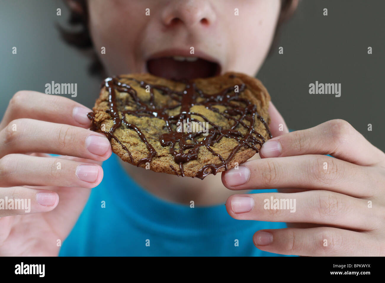 Eine Nahaufnahme eines jungen dabei, einen Bissen von einem Cookie zu nehmen. Stockfoto