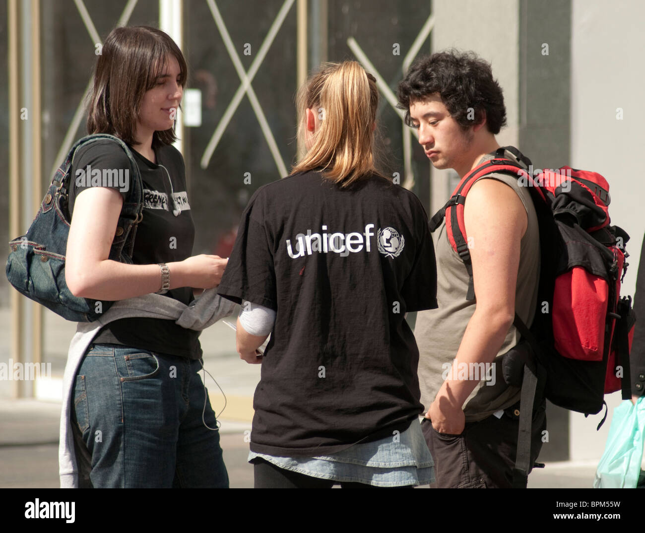 Ein weiblicher Liebe Arbeiter hält ein Mann und eine Frau in einer Glasgow-Straße um ihn für eine monatliche Spende Lastschriftverfahren anmelden. Stockfoto