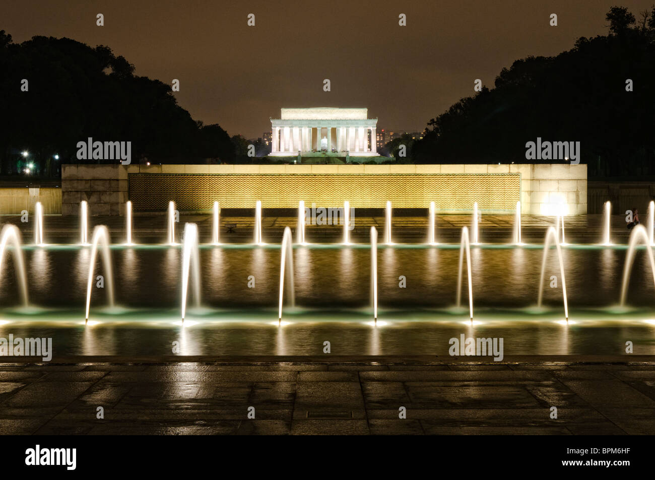 WASHINGTON DC, USA – der beleuchtete Rainbow Pool dient als Herzstück des National World war II Memorial. Die Düsen des Brunnens erzeugen Muster im dunklen Wasser unter den Granitbögen der Gedenkstätte. Das Design der Nachtbeleuchtung hebt die architektonischen Elemente der Gedenkstätte hervor und erzeugt gleichzeitig Reflexionen über die Wasseroberfläche. Stockfoto