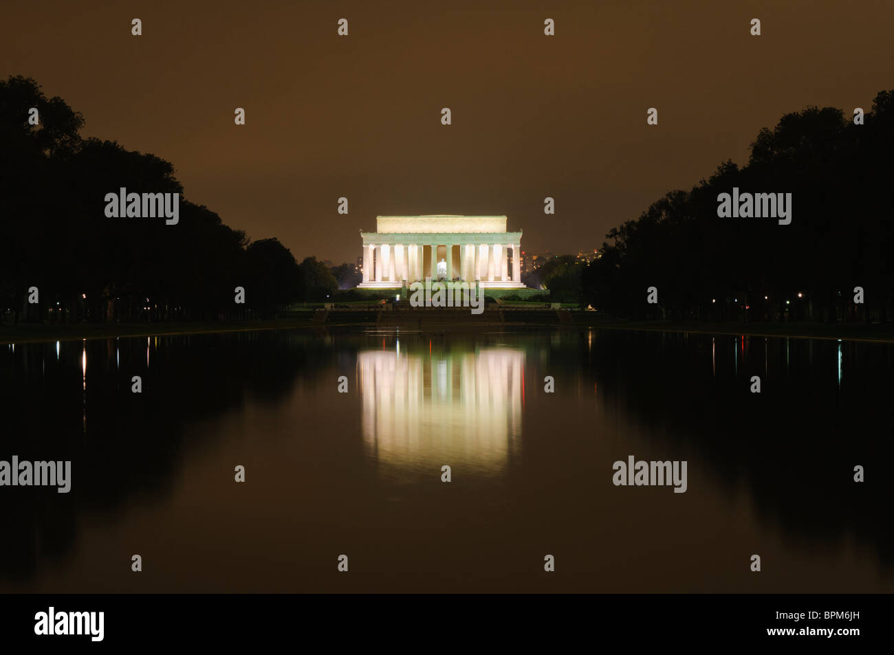 Lincoln Memorial Reflecting Pool at Night Washington DC // WASHINGTON DC – das Lincoln Memorial leuchtet am Nachthimmel, seine beleuchteten Säulen spiegeln sich in der spiegelähnlichen Oberfläche des Reflecting Pools. Das Bild der Gedenkstätte verdoppelt sich auf dem stillen Wasser, wodurch eine symmetrische Szene entsteht. Der 2.029 Meter lange Reflecting Pool erstreckt sich nach Osten in Richtung Washington Monument. Stockfoto