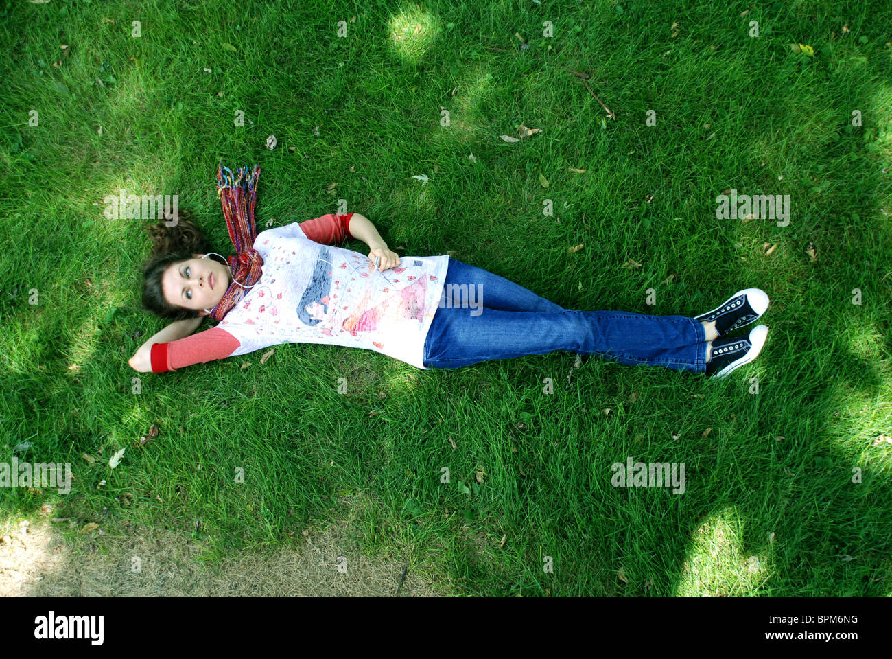 Frau liegend auf einer grasbewachsenen Parkanlage entspannen und anhören von Musik auf einen Ipod. Stockfoto