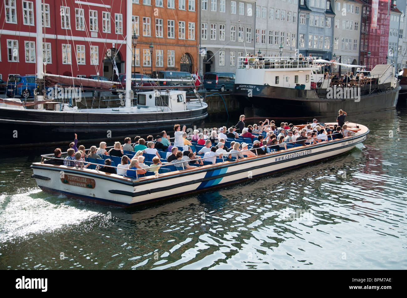 Eine Grachtenfahrt Boot die Passagiere auf eine Tour durch Kopenhagen und seine Umgebung im Hafen von Nyhavn, Kopenhagen, Dänemark. Stockfoto