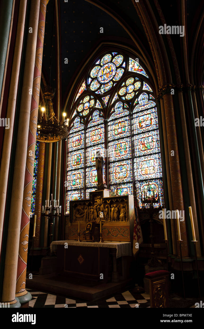 Notre-Dame de Paris Kapelle Buntglasfenster Altar Paris Frankreich // PARIS, Frankreich — Eine Kapelle im Inneren von Notre Dame de Paris verfügt über einen markanten Altar, der durch ein prächtiges Buntglasfenster beleuchtet wird. Das komplizierte gotische Buntglas, ein Wahrzeichen der Kathedrale, zeigt verschiedene religiöse Szenen und Figuren. Der reich verzierte Altar ist mit detaillierten Schnitzereien verziert, darunter ein Relief, das die Absetzung Christi darstellt, und wird von einer Statue gekrönt, die zum heiligen Raum beiträgt. Notre Dame de Paris, eine mittelalterliche katholische Kathedrale, ist ein bedeutendes Wahrzeichen im Herzen von Paris, Île-de-France, Franc Stockfoto